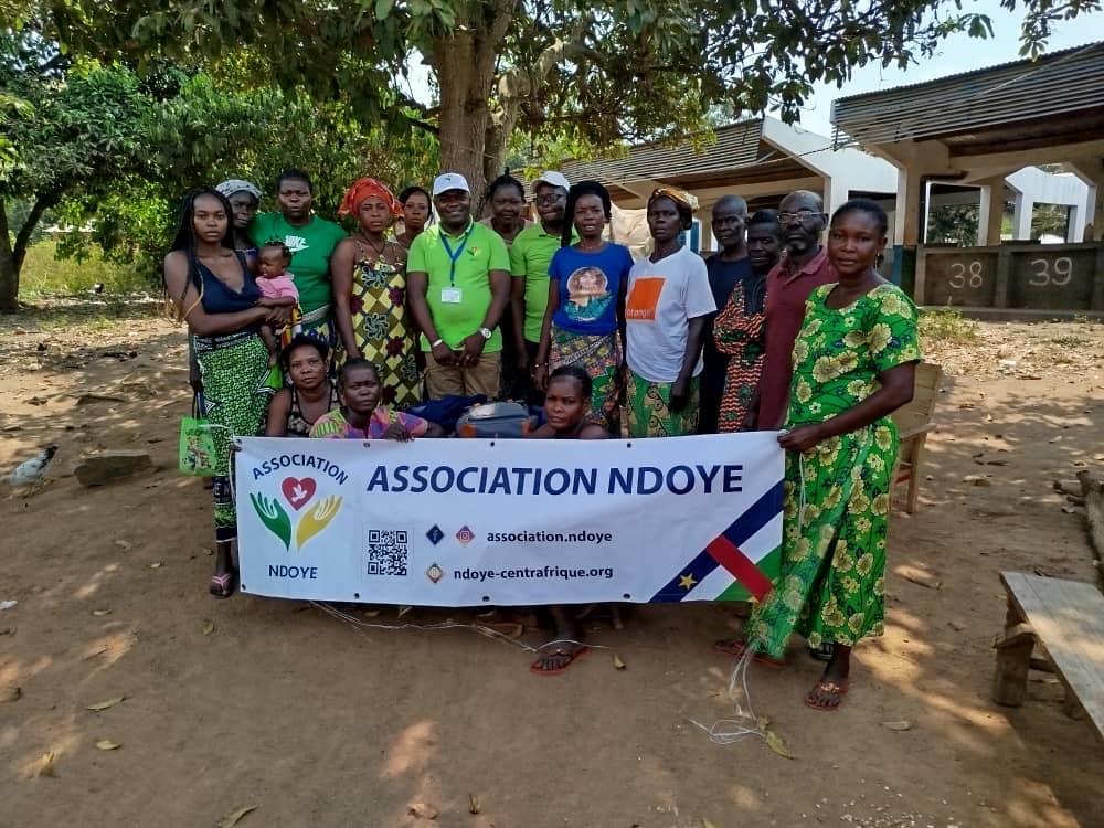 L’équipe NDOYE en mission d’évaluation et d’identification au sein d'un village, villageois tenant la bannière de l'association